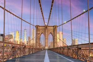 New York on the Brooklyn Bridge Promenade facing Manhattan's skyline at dawn.
