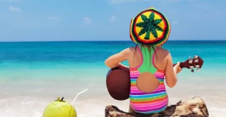 happy baby in rastaman hat have fun, play reggae music on Hawaiian guitar
