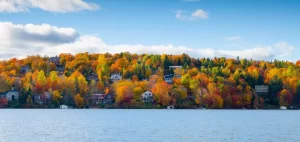 Colorful trees in mountain with green, yeloow, orange and red leaves with lake in foreground.