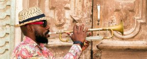 Cuban musician playing trumpet standing in front of the old door in Havana, Cuba