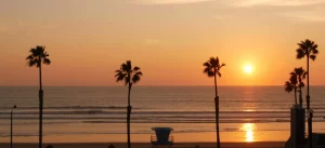 Palms silhouette sunset sky, California aesthetic. Oceanside USA. Tropical pacific ocean beach atmosphere. Dark black palm tree, Los Angeles vibes. Lifeguard watchtower, baywatch watch tower hut.