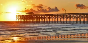 Beautiful marine landscape with golden sunrise over calm atlantic ocean beach with wooden pier