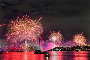 Red bright light balls of annual New Year midnight fireworks in Sydney city over waters of Sydney harbour