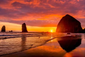 Colorful sunset, birds, Haystack Rock sea stacks, Canon Beach, Clatsop County, Oregon. Originally discovered by Clark of Lewis Clark in 1805