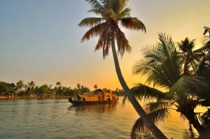 Una casa galleggiante a vela nelle acque del Kerala durante il tramonto.