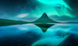 Aurora borealis Northern lights over Kirkjufell mountain volkano. Amazing night scene near famous Kirkjufell waterfall, Iceland.