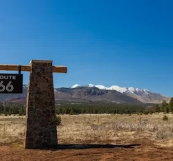 route 66 sign with snow capped mountains in background