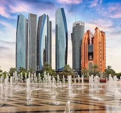 Skyscrapers in Abu Dhabi at dramatic sunset with fountain; United Arab Emirates