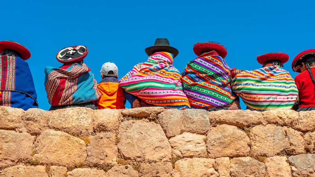 Donne indigene quechua in abiti tradizionali su un muro inca a Chinchero, provincia di Cusco, Perù | Tour Perù Reale | Esclusiva Alidays Travel Experience