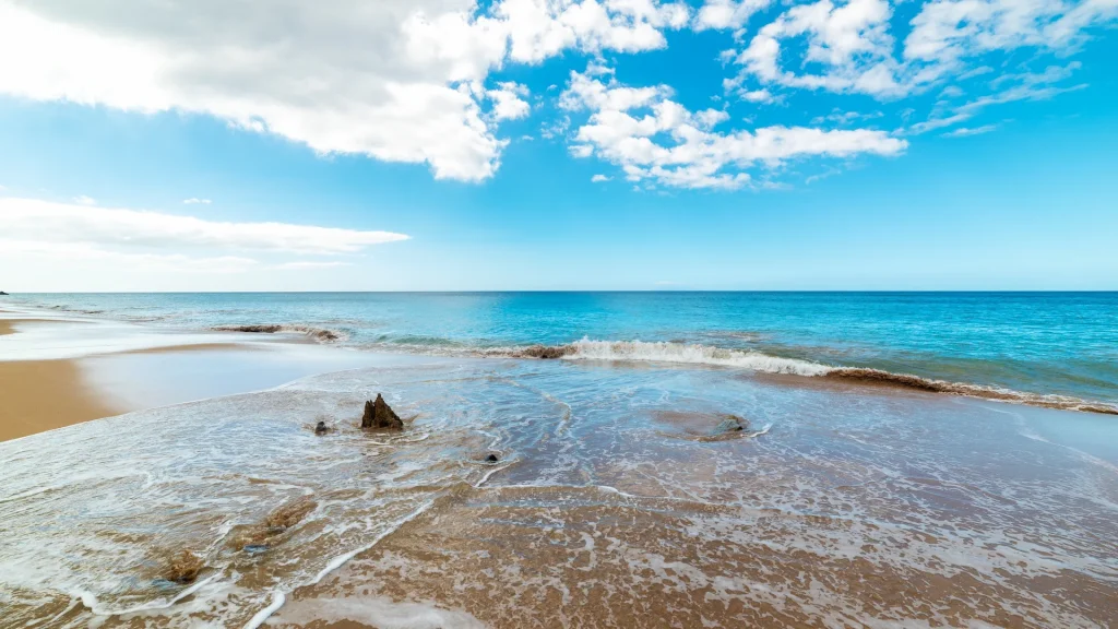 Sabbia dorata e mare blu su una spiaggia tropicale in una giornata nuvolosa. Spiaggia di La Perle, Guadalupa, Mar dei Caraibi