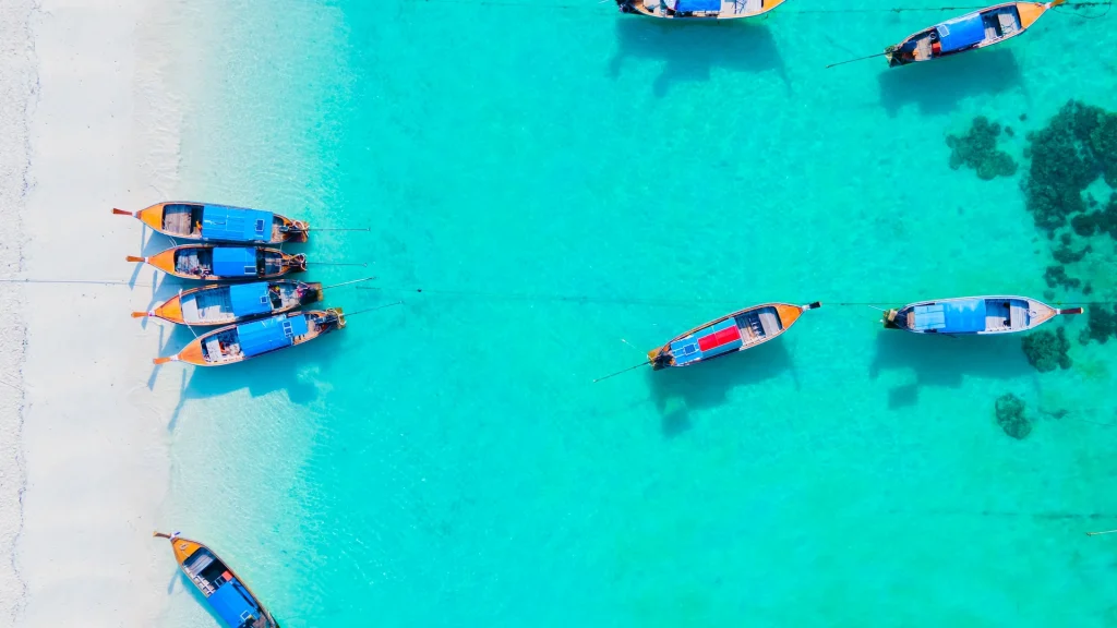 Barche nell'oceano blu dell'isola di Koh Lipe, nel sud della Thailandia | Tour Bangkok e mare Thailandia | Esclusiva Alidays Travel Experience