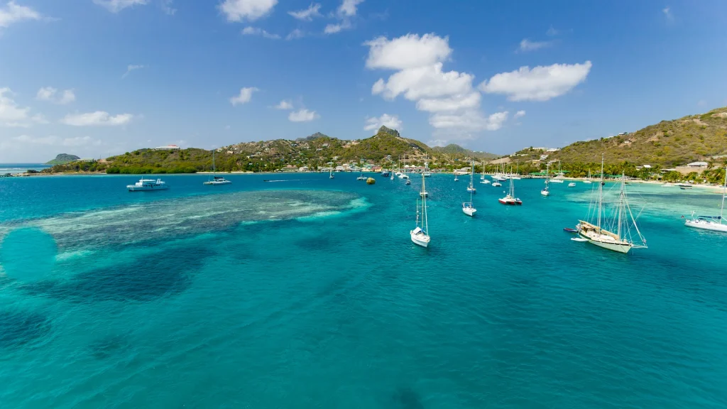 Barche a vela all'ancora nelle acque turchesi dietro la barriera corallina di Union Island, Saint Vincent e Grenadine, Indie Occidentali | Viaggio a Barbados e Saint Vincent | Alidays Travel Experience