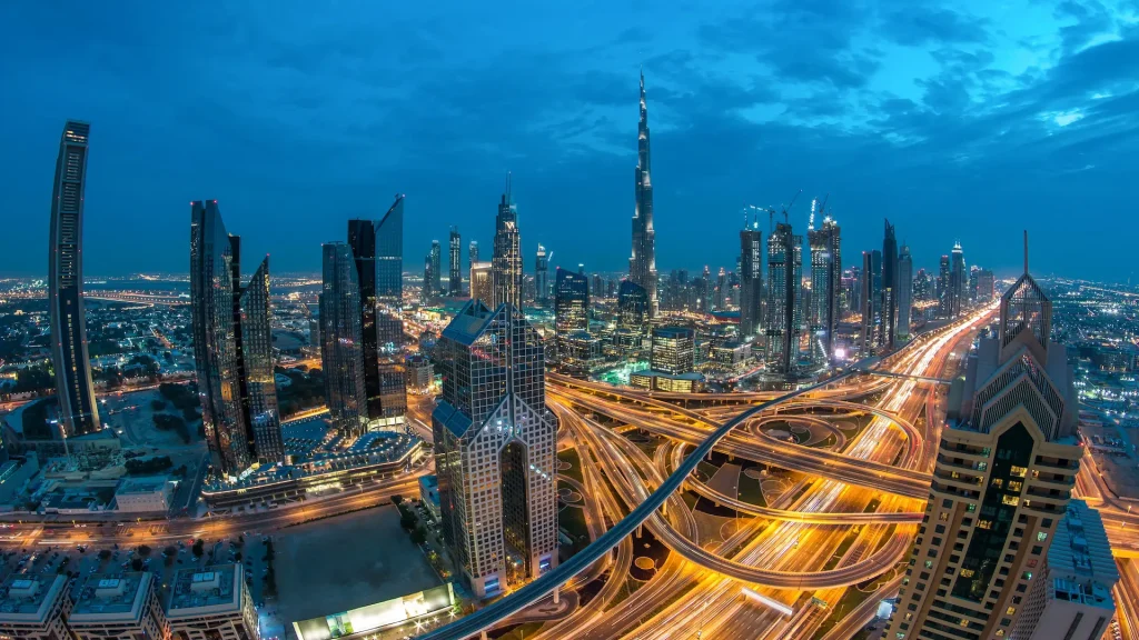 Moderni grattacieli e affollate autostrade serali notturne nel lussuoso centro di Dubai. Vista aerea dall'alto dal tetto della torre. Traffico stradale. Lente Fisheye. Dubai, Emirati Arabi Uniti