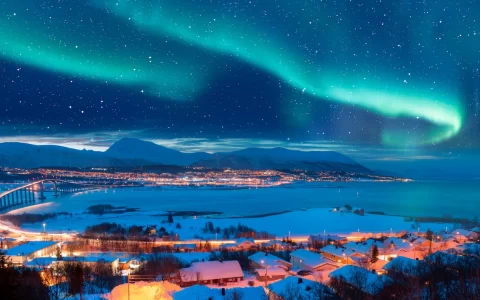 Aurora borealis or Northern lights in the sky over Tromso with Sandnessundet Bridge - Tromso, Norway