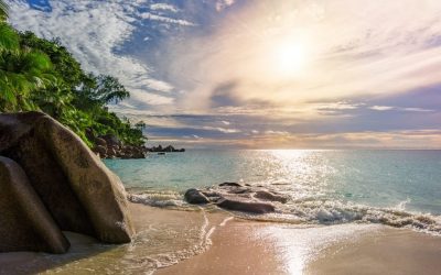 sunny day on paradise beach with big granite rocks, turquoise water, white sand and palm trees at anse georgette,praslin seychelles