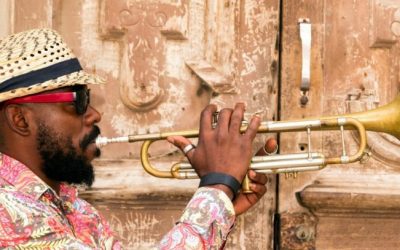 Cuban musician playing trumpet standing in front of the old door in Havana, Cuba