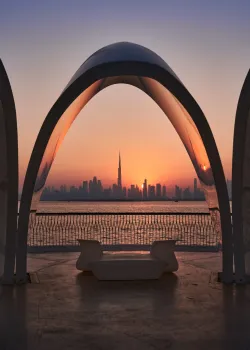 Sagoma dello skyline di Dubai al tramonto, incorniciata da una struttura ombreggiante ad arco