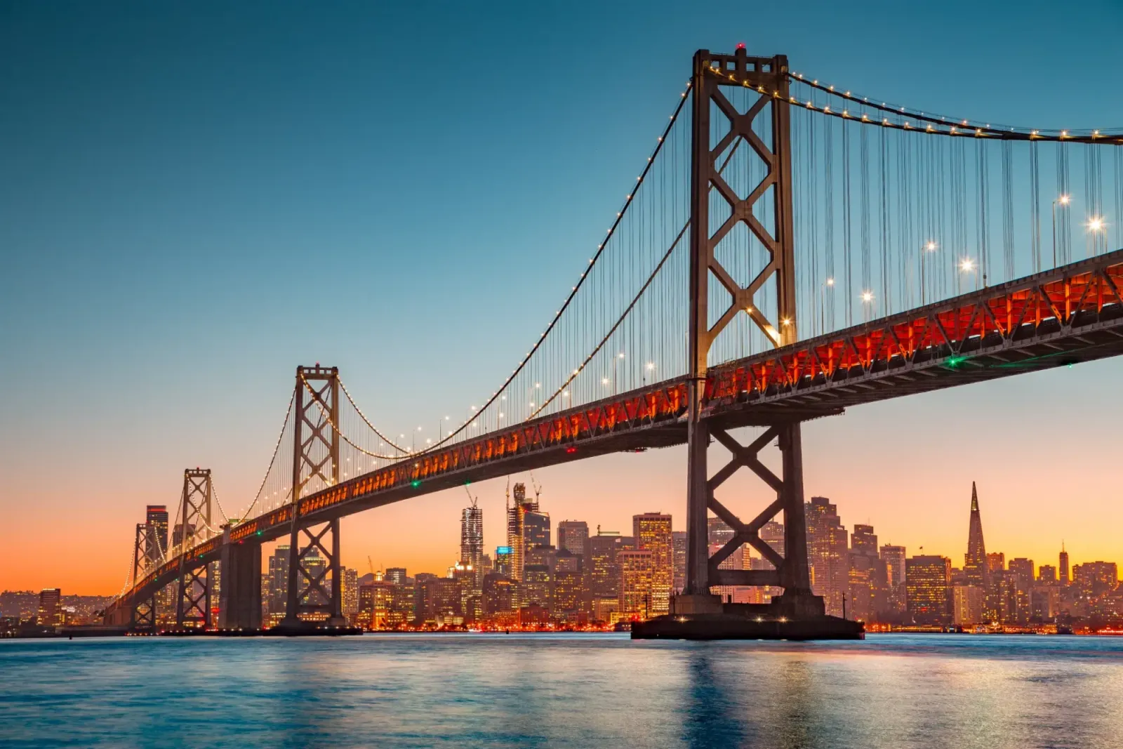 Vista panoramica sullo skyline di San Francisco con il famoso Oakland Bay Bridge illuminato al tramonto in estate, San Francisco Bay Area, California, USA